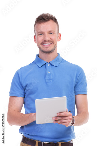 casual young man smiles while holding tablet