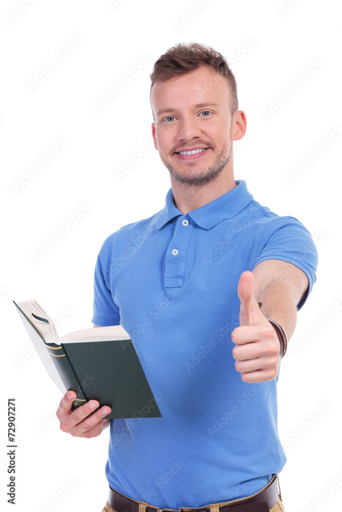 young casual man with book shows thumb up young casual man with book shows thumb up