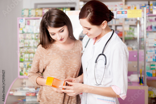 Pharmacist woman showing product to custumer photo