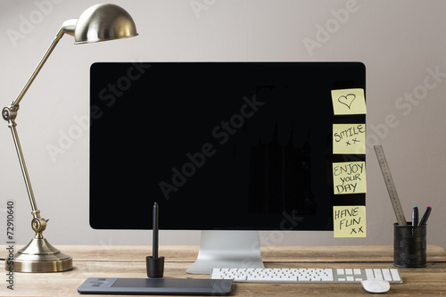 Image of a big computer screen with a lamp and stationary items