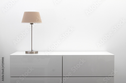 Foto white commode with table lamp in bright minimalism interior