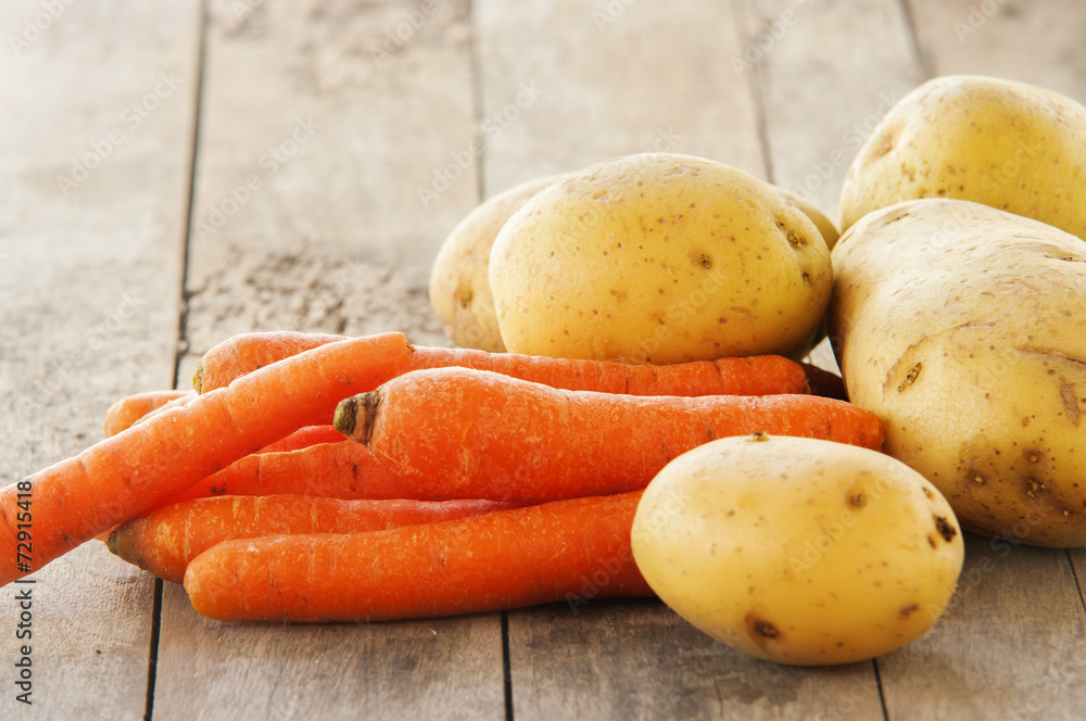 Young potatoes and carrots on wooden background Young potatoes and carrots on wooden background