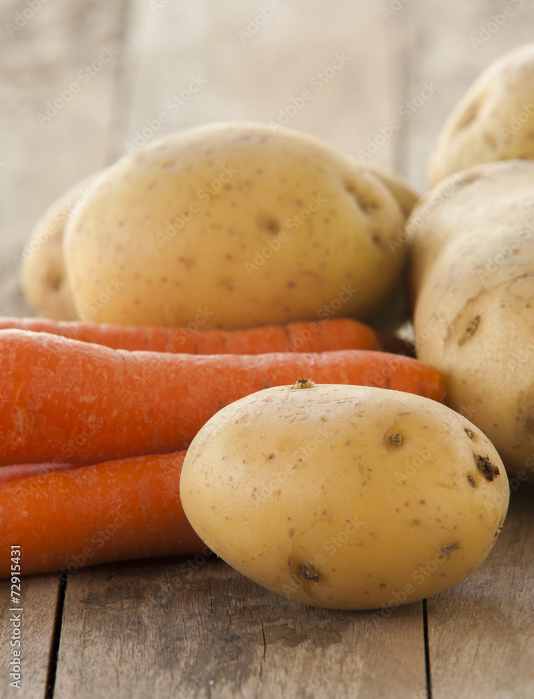 young potatoes and carrots on wooden background young potatoes and carrots on wooden background