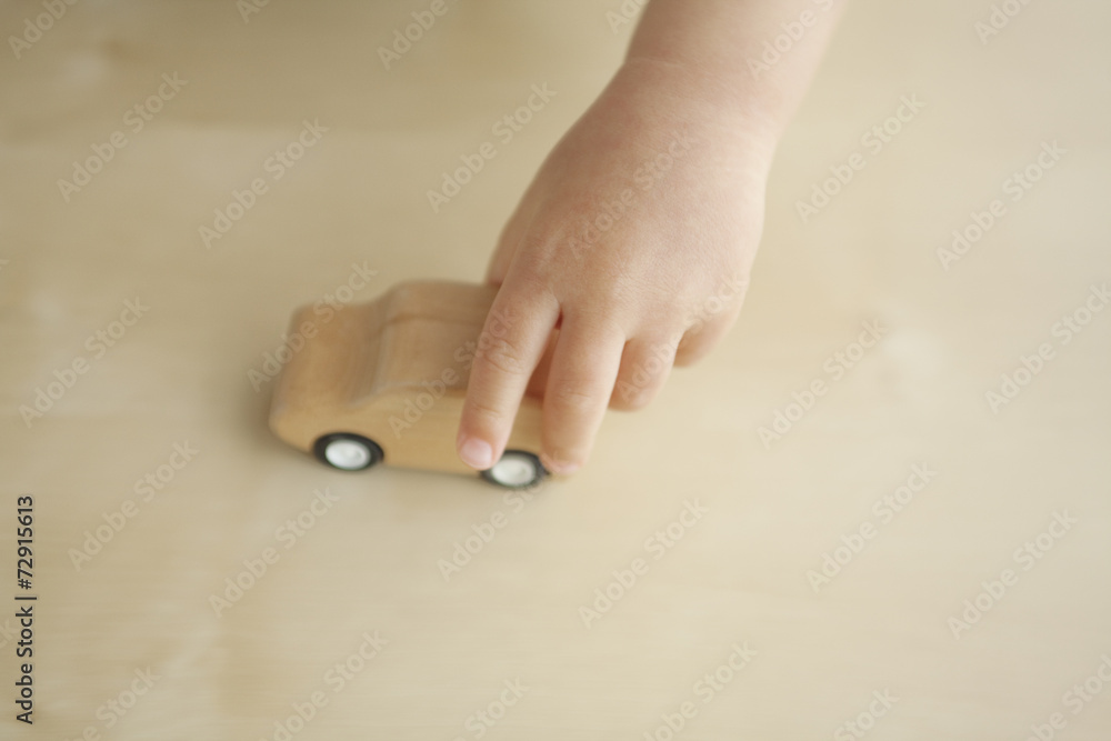 木製の車のおもちゃで遊ぶ子供の手