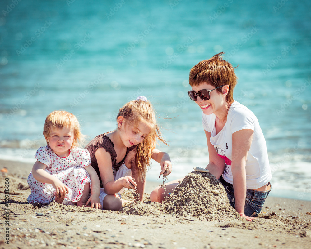 mother and daughters playing in the sand mother and daughters playing in the sand