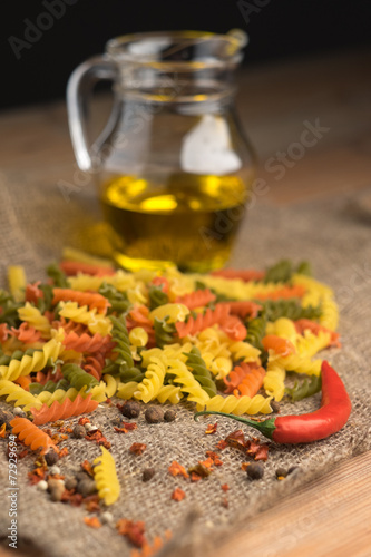 Tricolor spiral pasta with spices on a dark wooden table. photo