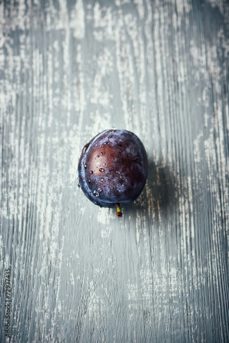 A freshly washed plum on a wooden surface