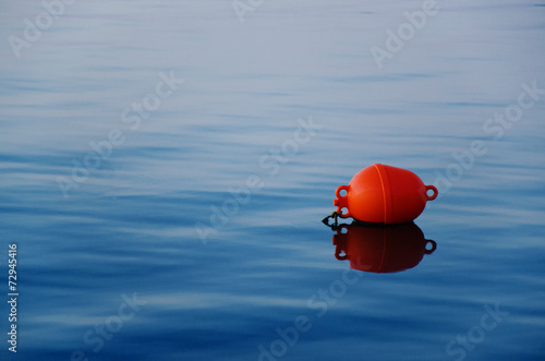 Orange buoy on the tranquil blue water photo