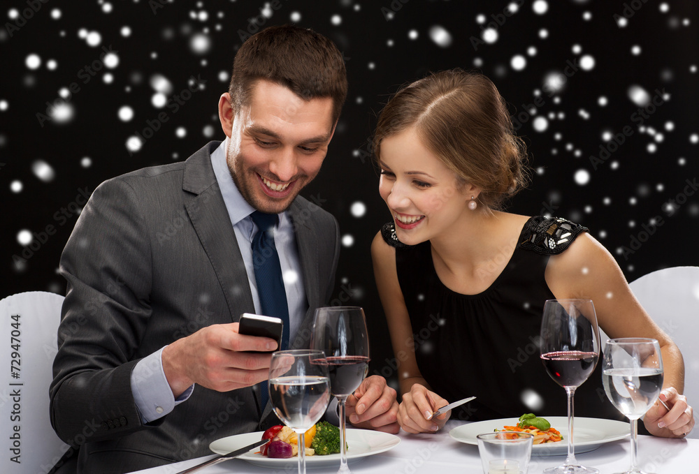 smiling couple with smartphone at restaurant smiling couple with smartphone at restaurant