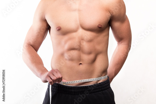 Muscular fitness man measuring his waist