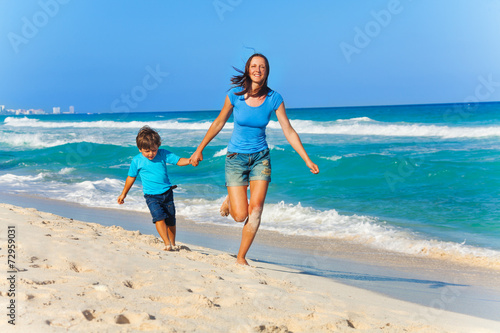 Smiling mother and son hold arms while running © Sergey Novikov