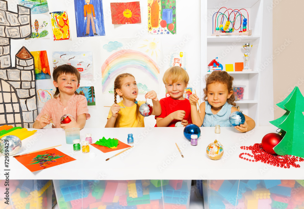 Children painting together New Year balls and sit Children painting together New Year balls and sit