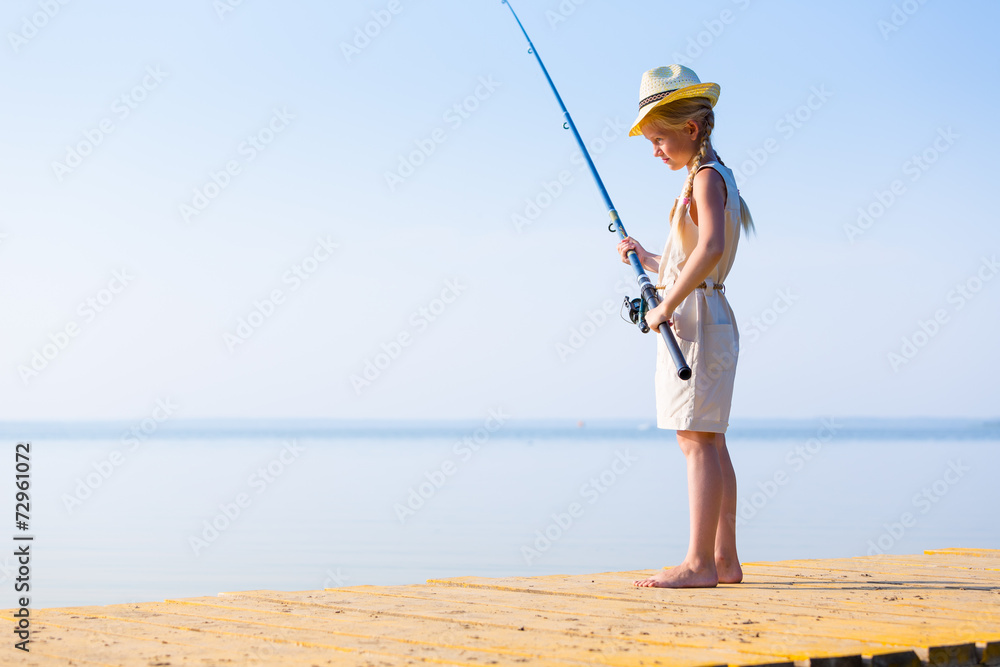 Girl in a dress and a hat with a fishing rod