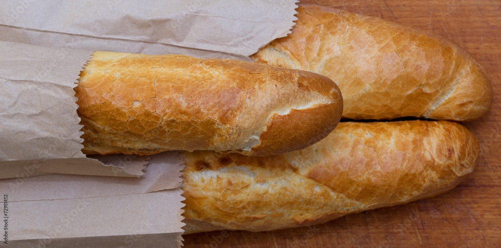 Baguettes packaged in a paper on a kitchen board