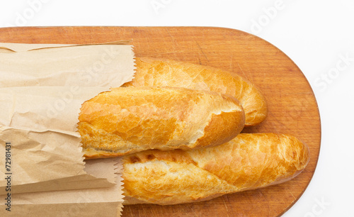 Obraz na płótnie Baguettes packaged in a paper on a board on white background w salonie