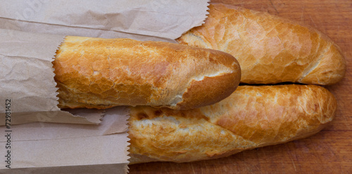 Obraz na płótnie Baguettes packaged in a paper on a kitchen board w salonie