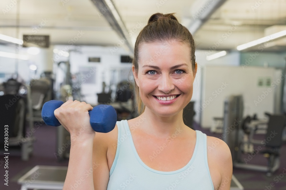 Obraz premium Fit brunette holding blue dumbbells