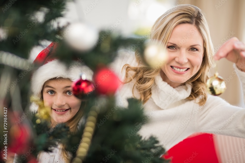 Festive mother and daughter decorating christmas tree Festive mother and daughter decorating christmas tree