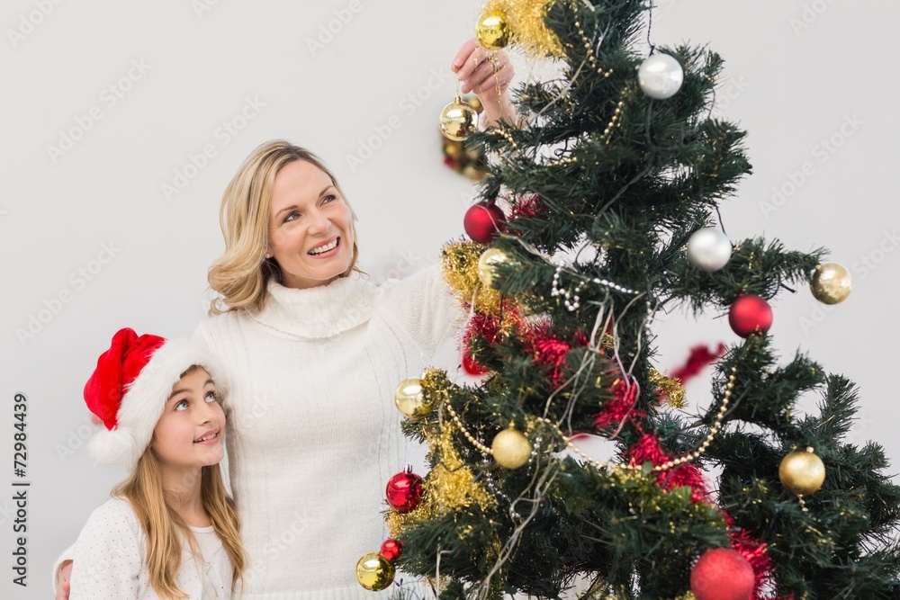 Festive mother and daughter decorating christmas tree Festive mother and daughter decorating christmas tree