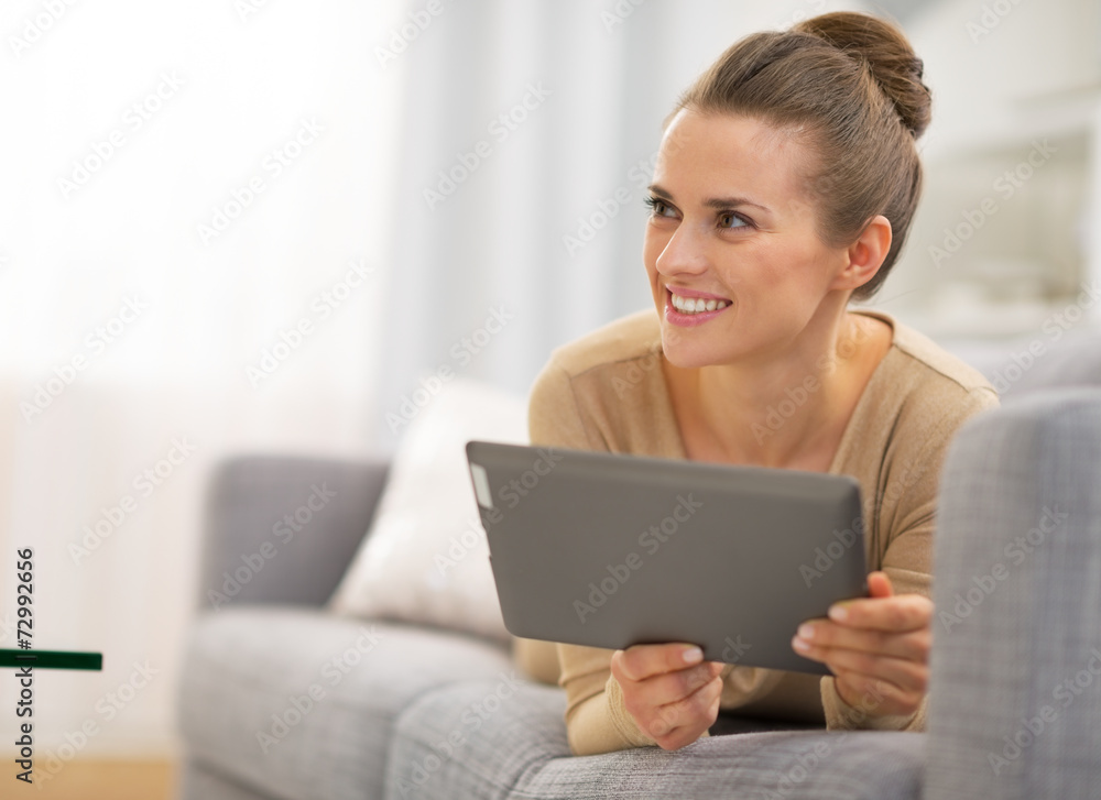 Thoughtful young woman laying on couch and using tablet pc Thoughtful young woman laying on couch and using tablet pc