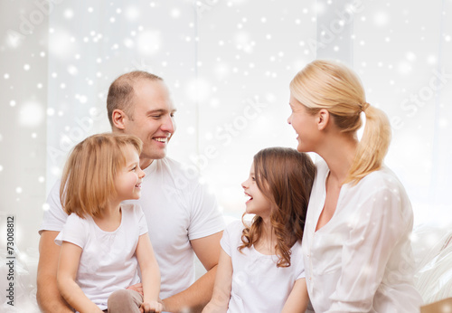 smiling parents and two little girls at home