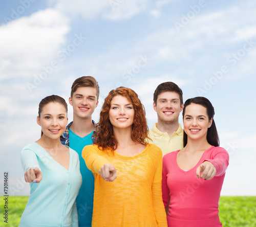group of smiling teenagers over blue sky and grass © Syda Productions