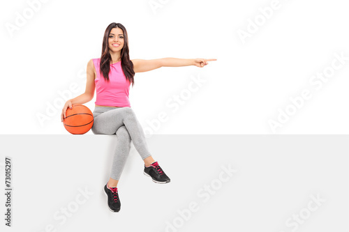 Girl holding a basketball and pointing with finger