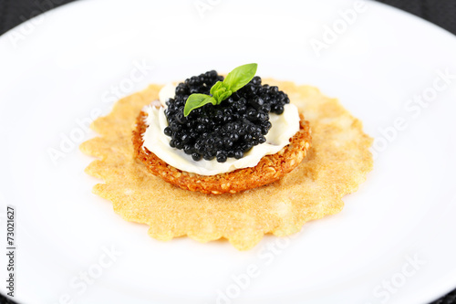 Black caviar with crispy bread on plate closeup