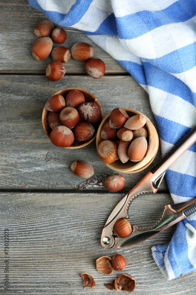 Hazelnuts in wooden bowls, on napkin on wooden background