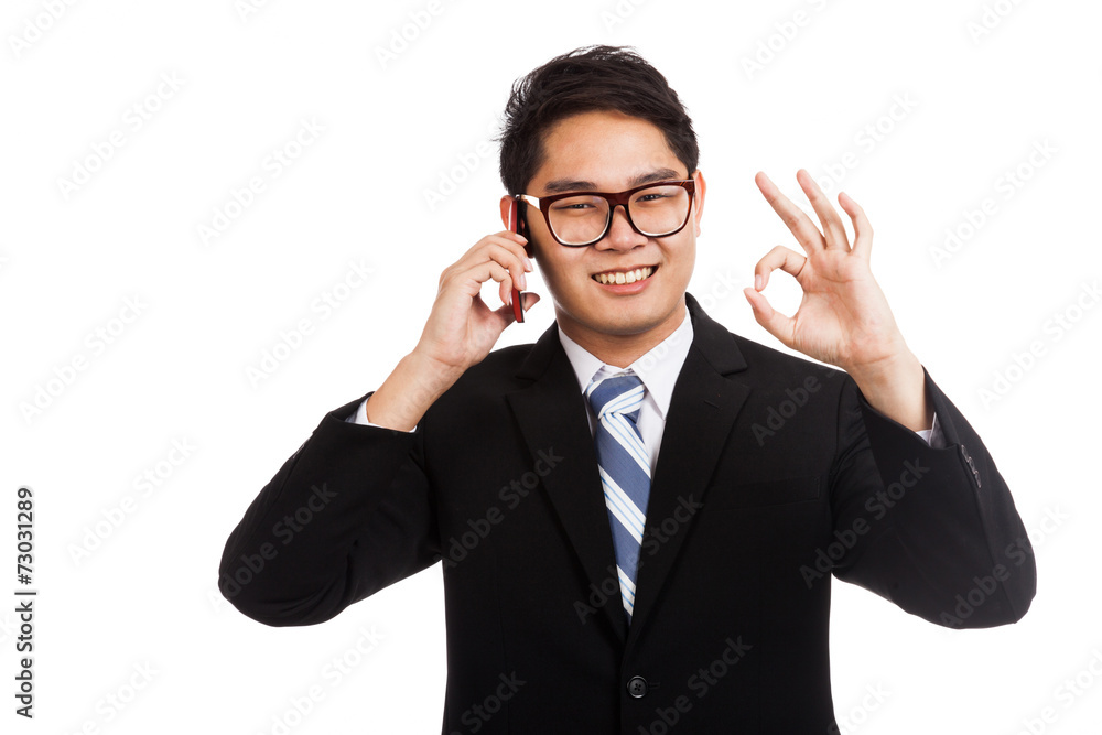 Asian businessman smile show OK sign talk on mobile phone Asian businessman smile show OK sign talk on mobile phone