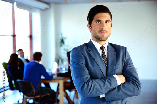 Serious businessman standing with arms folded