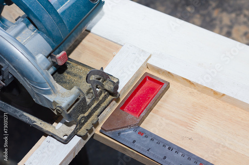 circular saw cutting wood and iron ruler