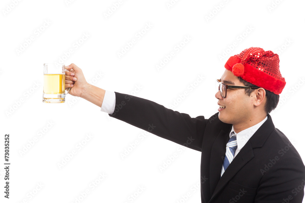 Asian businessman with red christmas hat cheers with mug of bee Asian businessman with red christmas hat cheers with mug of bee