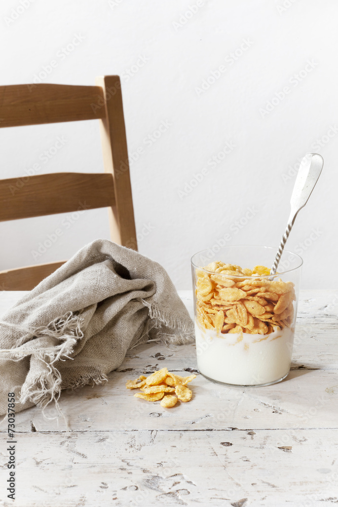 breakfast with white yogurt and corn flakes on glass with spoon breakfast with white yogurt and corn flakes on glass with spoon