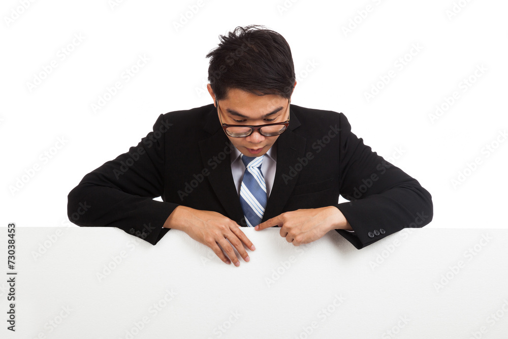 Asian businessman look down behind blank banner Asian businessman look down behind blank banner