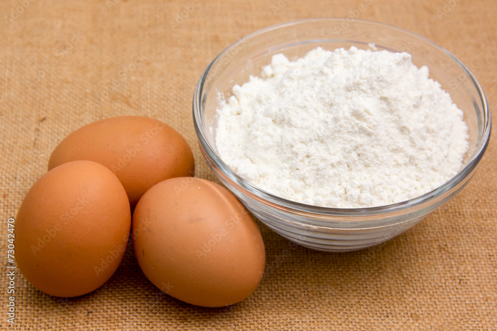 Eggs and flour in bowl on jute cloth Eggs and flour in bowl on jute cloth