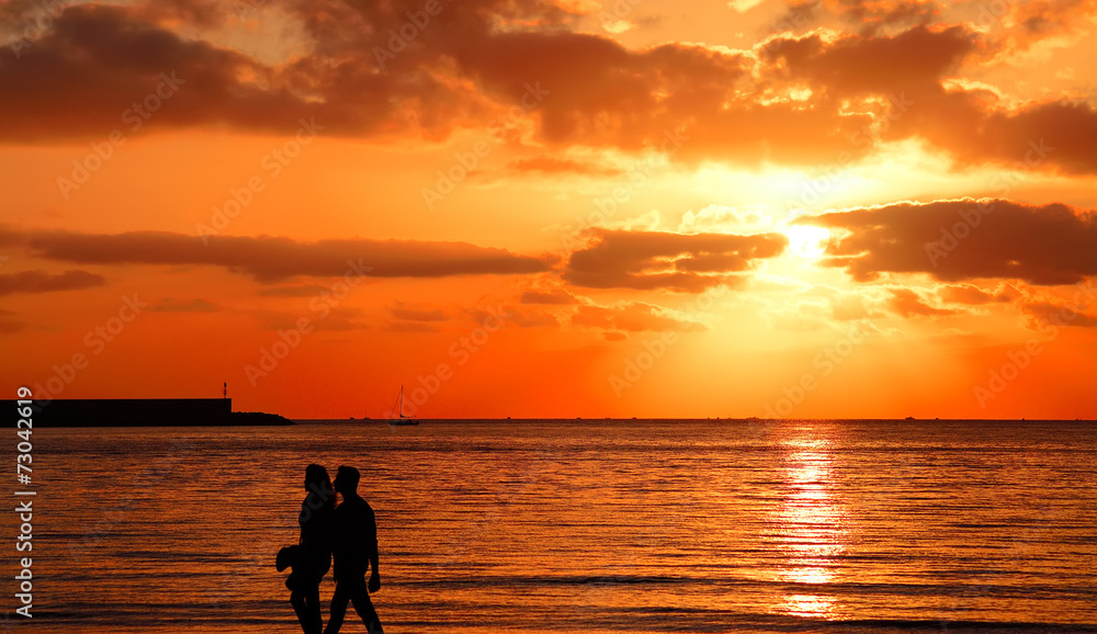 young couple walking by the sea at sunset young couple walking by the sea at sunset
