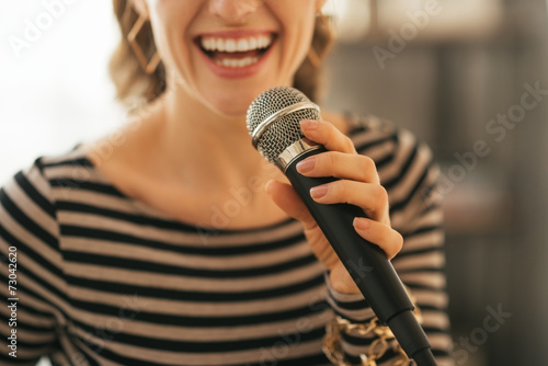 Fototapeta Closeup on young woman singing with microphone in loft apartment
