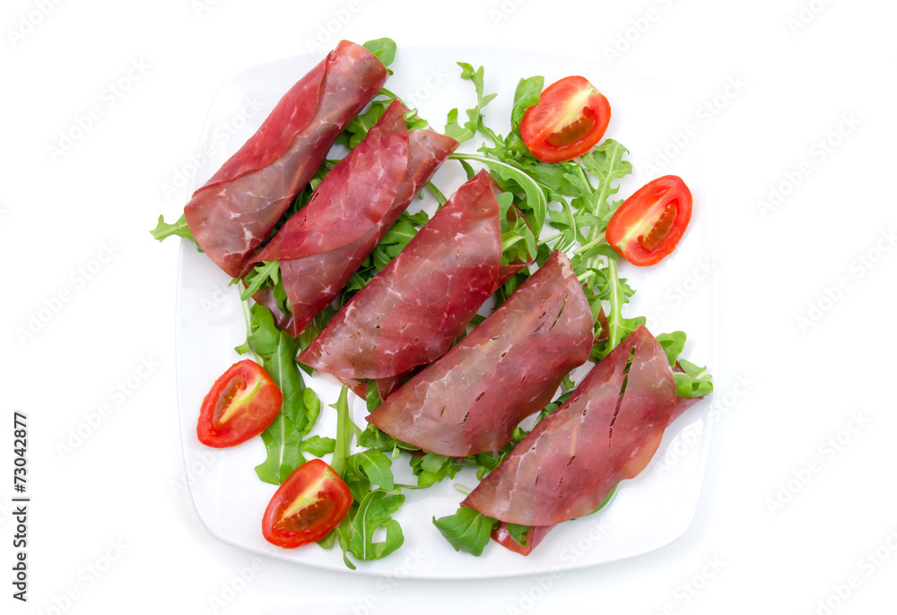 Rolls of dried beef on plate on white background seen from above Rolls of dried beef on plate on white background seen from above
