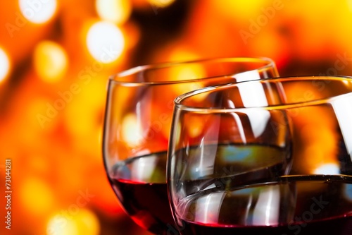 red wine glasses against colorful unfocused lights background