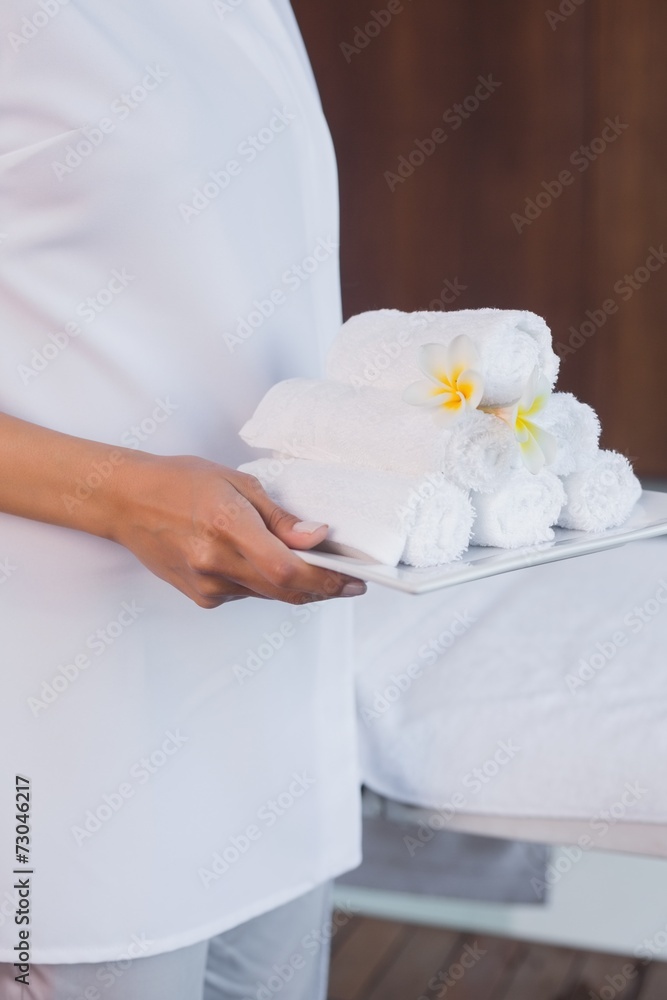 Mid section of masseur holding rolled up towels Mid section of masseur holding rolled up towels