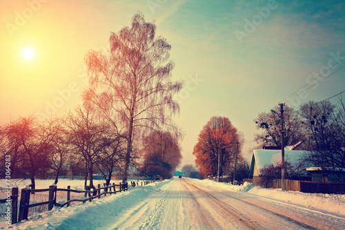 Snowy rural landscape with road at sunset