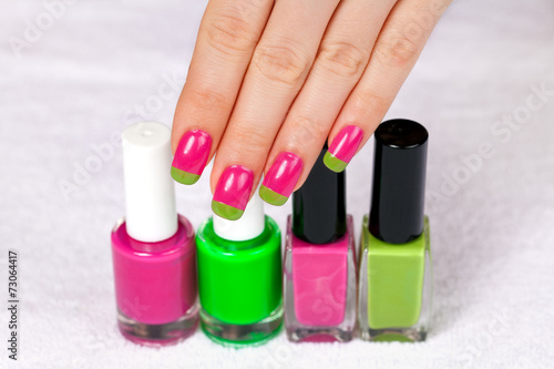 Female hand with a two-color manicure touch the nail polish