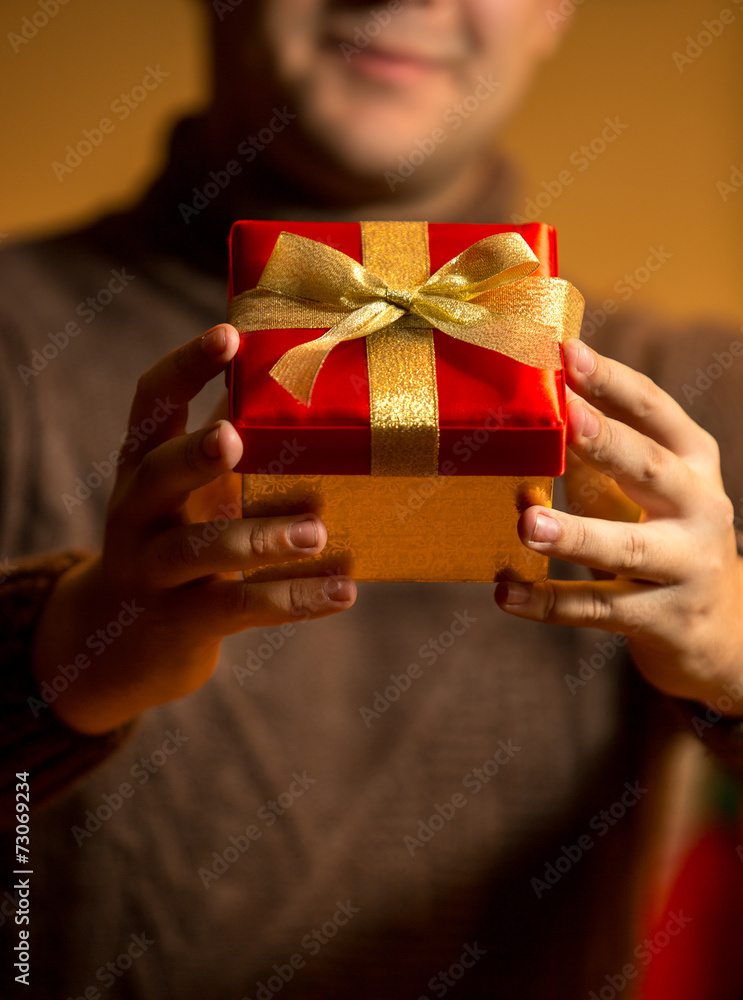 happy man holding red gift box with golden bow