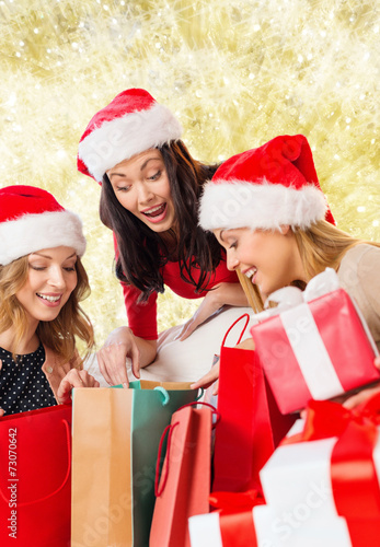 smiling young women in santa hats with gifts