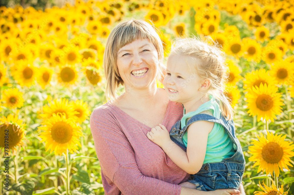 Mom with daughter in between beautiful sunflowers in summer day. Mom with daughter in between beautiful sunflowers in summer day.