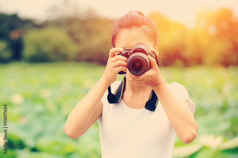 young woman photographer taking photo of blooming lotus at park young woman photographer taking photo of blooming lotus at park