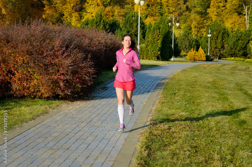 Woman running in autumn park, beautiful girl runner jogging
