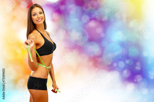 Beautiful young woman with measuring tape on bright background