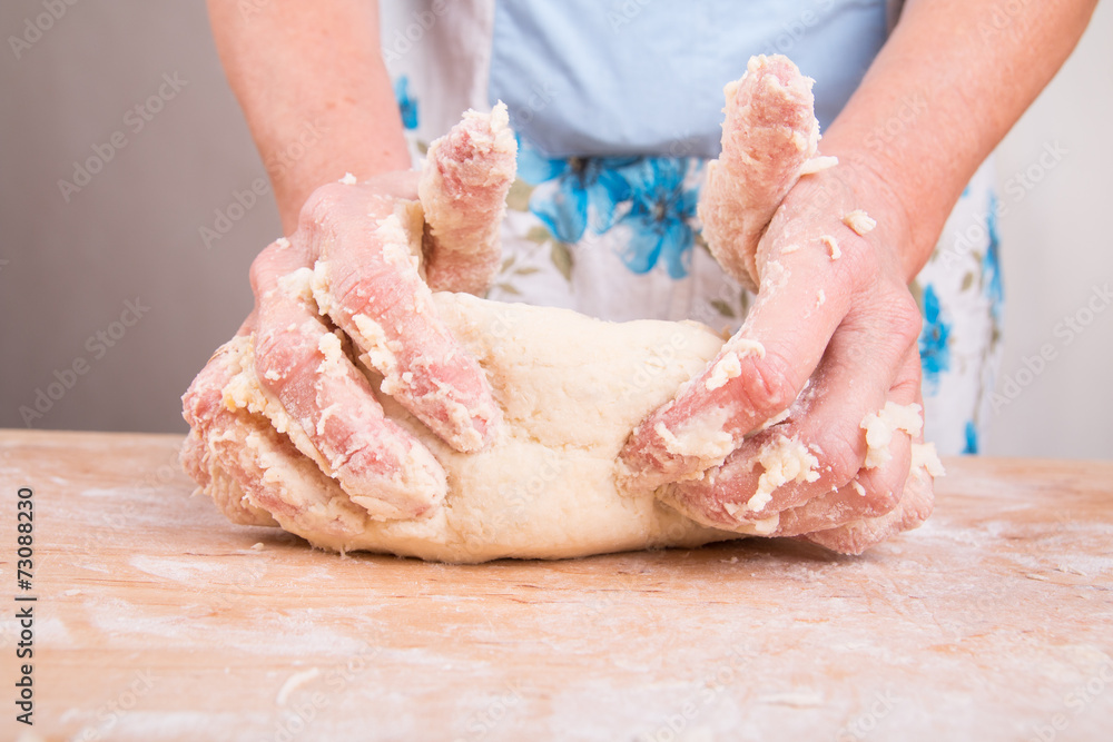 Hands kneading dough on board